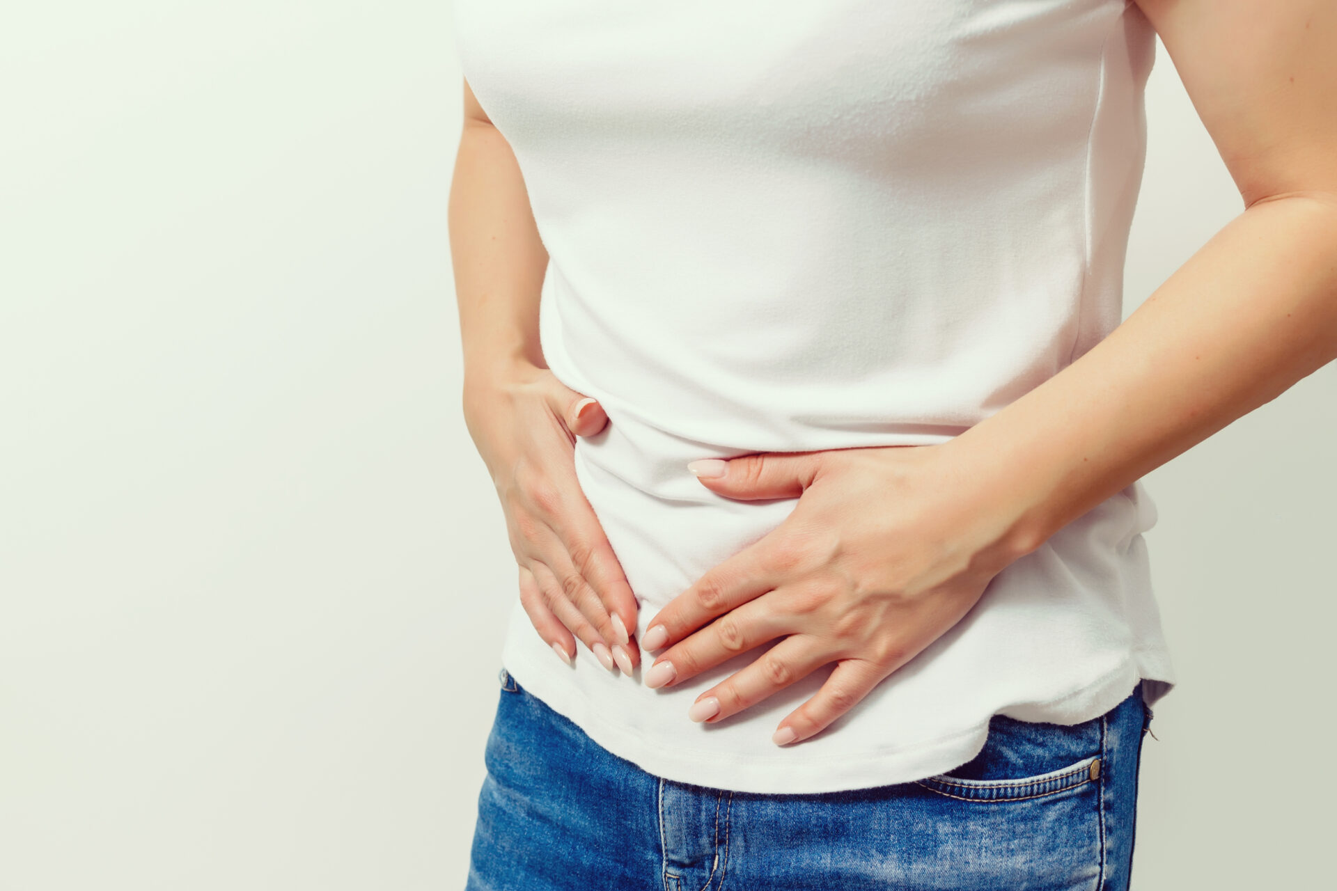 Young female suffering form stomach ache on gray background w/ c